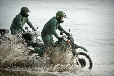 Dos guardias civiles del SEPRONA de la Guardia Civil prestando servicio con motocicletas en una playa.